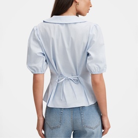 Model wearing Forever New soft blue puff-sleeve blouse with tie-back detail, styled with light-wash jeans. Rear view.