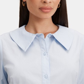 Model wearing Forever New soft blue shirt dress with oversized collar and button-front detail, gold hoop earrings visible