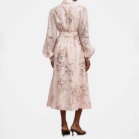 Model wearing blush pink floral midi dress with long balloon sleeves, belted waist, and button-front detail, styled with black heels.