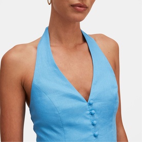 Model wearing Forever New blue halterneck top with V-neckline and button detail, styled with gold hoop earrings