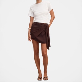 Model wearing dark brown wrap mini skirt with tie detail, styled with white fitted T-shirt and brown strappy sandals
