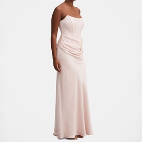 Model wearing blush pink strapless corset maxi dress with ruched side detail and flared hem