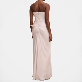Model wearing a blush pink strapless maxi dress with ruched back detail and side split, styled with a gold cuff bracelet.