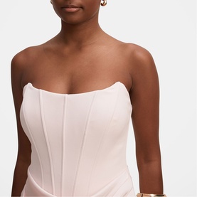 Model wearing strapless pale pink structured corset top with boning detail, styled with gold hoop earrings and bracelet