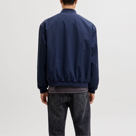 Model wearing navy blue bomber jacket with ribbed cuffs and hem, paired with dark denim jeans, seen from behind