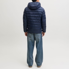 Model wearing Jack & Jones Kingsley Light Hooded Puffer Jacket in Navy Blazer, back view, styled with light blue wide-leg jeans.