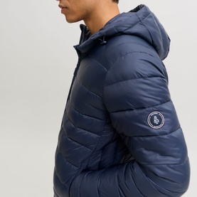 Model wearing Jack & Jones Kingsley Light Hooded Puffer Jacket in Navy Blazer, showing logo badge detail on sleeve.
