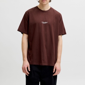 Model wearing Jack & Jones Bitter Chocolate crew neck T-shirt with small chest logo print, styled with black trousers.