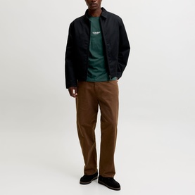 Model wearing Jack & Jones Soho Logo T-Shirt in Scarab, styled with black zip jacket and brown straight-leg trousers.
