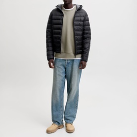 Model wearing Jack & Jones Berg Padded Hooded Puffer Jacket in black, styled with light wash jeans, khaki sweatshirt and tan boots.