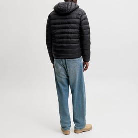 Model wearing Jack & Jones Berg Padded Hooded Puffer Jacket in black, back view, styled with light blue jeans and tan shoes.