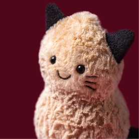 Jellycat Amuseables plush cat soft toy with cream curly fur, dark grey ears, and a smiling face, close-up detail shot