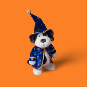 Jellycat plush dog toy dressed in blue star-print wizard cape and hat, holding a small golden star, on orange background