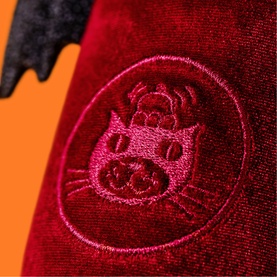 Jellycat Amuseables plush close-up showing embroidered cat face motif on red velvet fabric with black wing detail visible