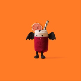 Jellycat Amuseables plush smoothie cup character with bat wings, orange slice, straw, and legs, in dark red and cream on orange background