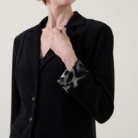 Model wearing Joseph Ribkoff black blazer, close-up detail of animal print contrast cuff in grey tones, single-button fastening visible.