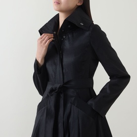 Model wearing Joseph Ribkoff black coat with fitted waist, spread collar, zip fastening, and self-tie belt detail