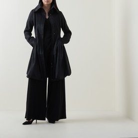 Model wearing Joseph Ribkoff black coat with flared silhouette, styled with wide-leg trousers and black heels.