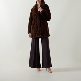 Model wearing Joseph Ribkoff Textured Faux Fur Coat in brown, notch lapel, longline silhouette, styled with wide-leg dark trousers and heeled sandals.
