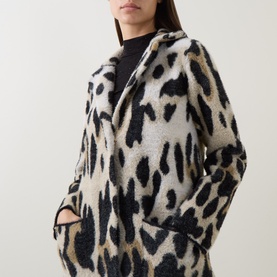 Model wearing Joseph Ribkoff Coat in camel and black leopard-print fleece, with hands in pockets, styled over a black top.