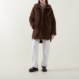 Model wearing Joseph Ribkoff Dark Mink faux shearling hooded zip-up coat, styled with white wide-leg trousers and black loafers.