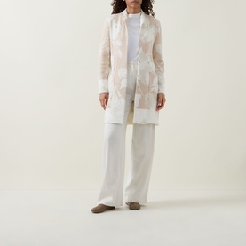 Model wearing Joseph Ribkoff Oatmeal and Winter White sheer floral cover-up over white wide-leg trousers and fitted top.