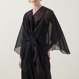 Model wearing Joseph Ribkoff Tie-Front Cover Up in black, semi-sheer fabric with wide angel sleeves and front tie fastening, styled over black outfit.