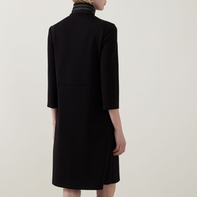 Model wearing Joseph Ribkoff Dress in black, rear view, 3/4-length sleeves, knee-length, with contrast avocado turtleneck collar detail.