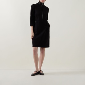 Model wearing Joseph Ribkoff black zip-neck dress with 3/4 sleeves and knee-length skirt, styled with black flat shoes.