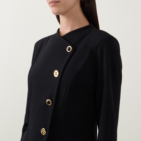 Model wearing Joseph Ribkoff Statement Button Pencil Dress in black, showing asymmetric gold statement button fastening and high neckline detail.