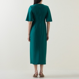 Model wearing Joseph Ribkoff Dress in Opulent Green, back view, flutter sleeves, fitted midi length with back split, styled with tan mules.