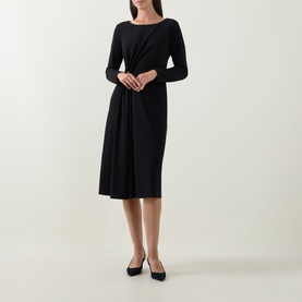 Model wearing Joseph Ribkoff black midi dress with long sleeves, draped waist detail and A-line skirt, styled with black heels.