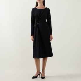 Model wearing Joseph Ribkoff black midi dress with long sleeves, draped waist detail with gold ring hardware, styled with black heels.