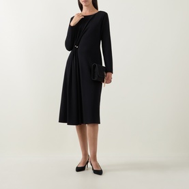Model wearing Joseph Ribkoff black long-sleeve midi dress with ruched waist detail, styled with black clutch bag and black pointed heels.