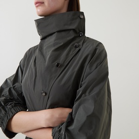 Model wearing Joseph Ribkoff Dress in Avocado, close-up showing high funnel neck and double-breasted button detail in khaki polyester fabric