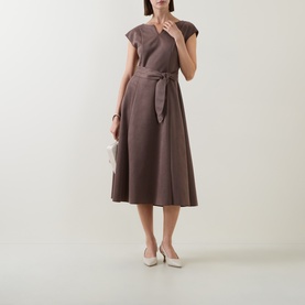 Model wearing Joseph Ribkoff mink midi dress with cap sleeves, tie waist belt and A-line skirt, styled with white court shoes and clutch bag.