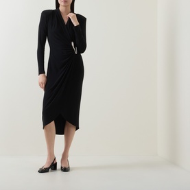 Model wearing Joseph Ribkoff black long-sleeve wrap-style midi dress with ruched drape detail, styled with black block-heel pumps.