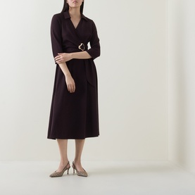 Model wearing dark burgundy wrap midi dress with three-quarter sleeves and gold buckle belt detail, styled with nude heeled courts