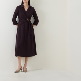 Model wearing dark burgundy midi wrap dress with three-quarter sleeves and gold buckle belt detail, styled with pointed-toe heels