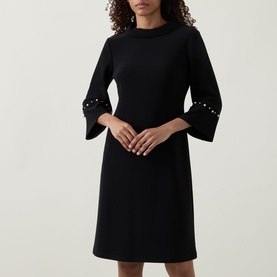 Model wearing Joseph Ribkoff Jewel Embellished Dress in black with fluted three-quarter sleeves and pearl-embellished cuffs, shift silhouette