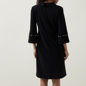 Model wearing Joseph Ribkoff Jewel Embellished Dress in black, rear view showing jewel-embellished flared cuffs and back zip fastening