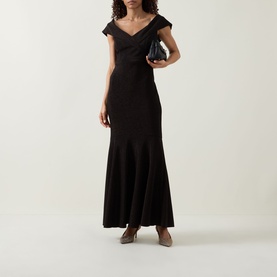 Model wearing Joseph Ribkoff bronze maxi dress with off-shoulder neckline and fishtail hem, styled with a clutch bag and nude heels.