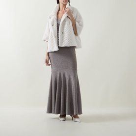 Model wearing Joseph Ribkoff Off-The-Shoulder Mermaid Dress in taupe lurex, styled with a white textured jacket and white heels.