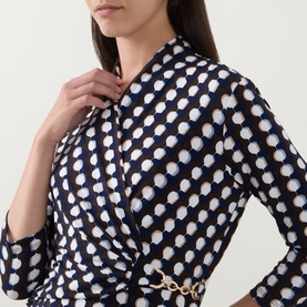 Model wearing Joseph Ribkoff Printed Wrap Dress in Brown/Multi with wrap front, three-quarter sleeves and gold chain hardware detail