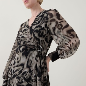 Model wearing Joseph Ribkoff grey multi animal print wrap dress with sheer long sleeves and belted waist detail.