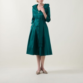 Model wearing Joseph Ribkoff Dress in Opulent Green with ruffle collar, three-quarter sleeves, belted waist, and full midi skirt; styled with nude