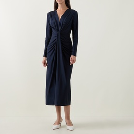 Model wearing Joseph Ribkoff Draped Cinched Dress in Midnight Blue; long sleeves, V-neckline, twisted front, midi length, styled with white heels.