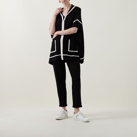 Model wearing Joseph Ribkoff black and white trimmed oversized jacket with black trousers and white trainers.