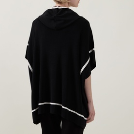 Model wearing Joseph Ribkoff Jacket in black with white contrast stripe trim, hooded, oversized poncho silhouette, back view.