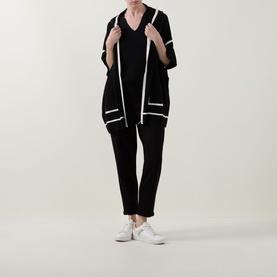 Model wearing Joseph Ribkoff black and birch open-front jacket with white trim details, styled with black trousers and white trainers.